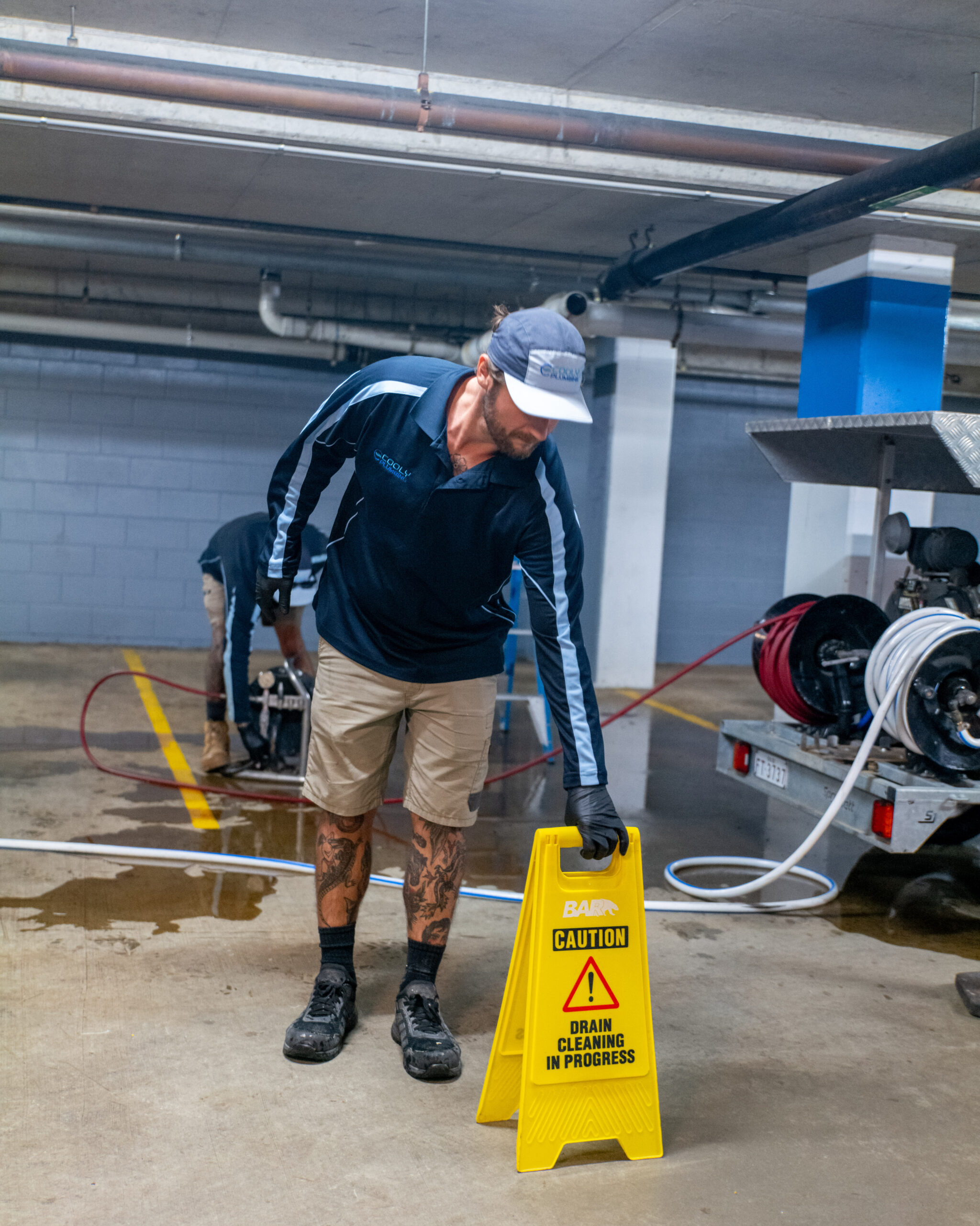 CoolyPlumbing-44 Licensed plumber responding to an emergency plumbing call, inspecting a burst pipe with tools and safety gear on-site."