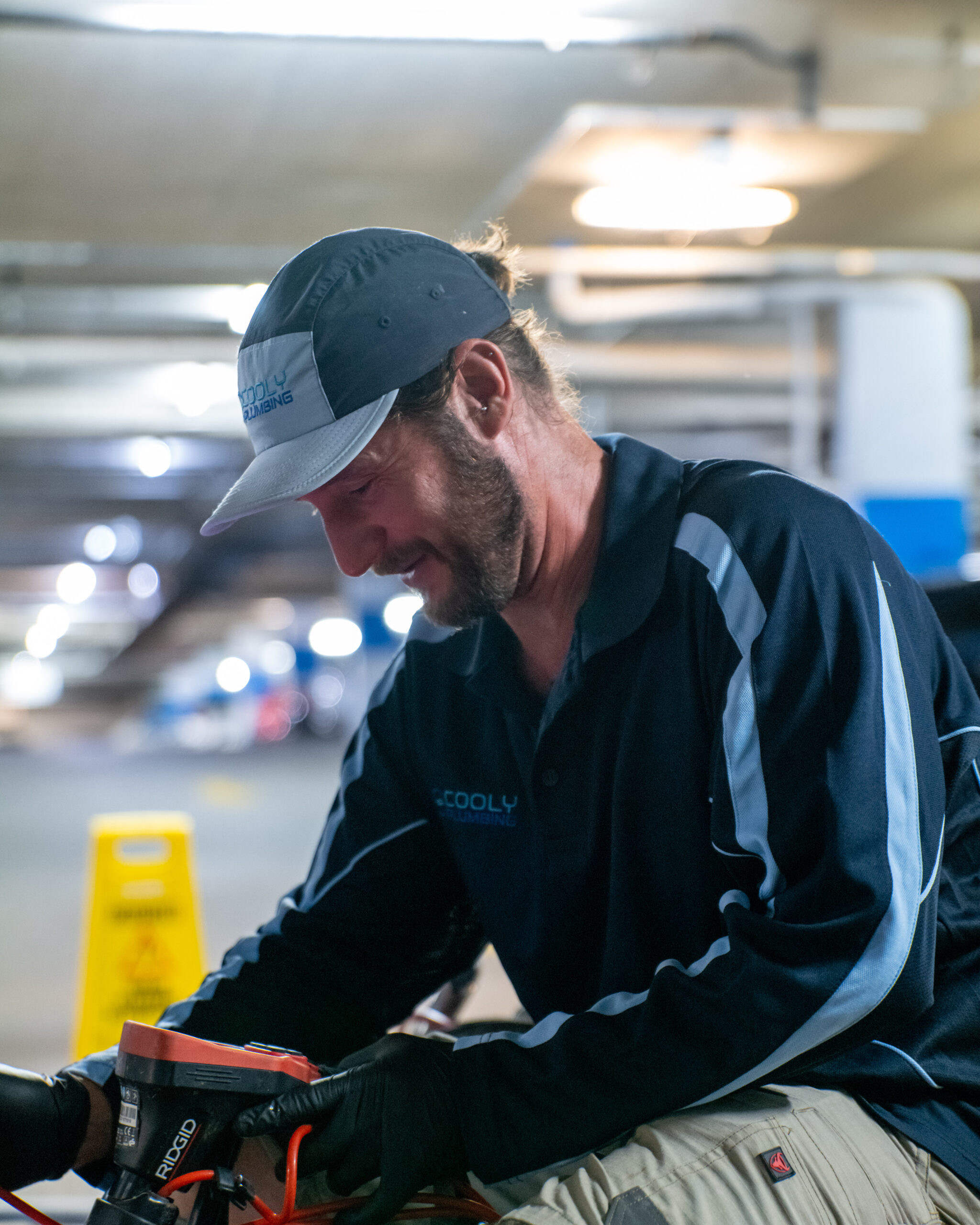 Plumber using a CCTV drain camera to inspect a blocked pipe, checking for damage or obstructions underground.