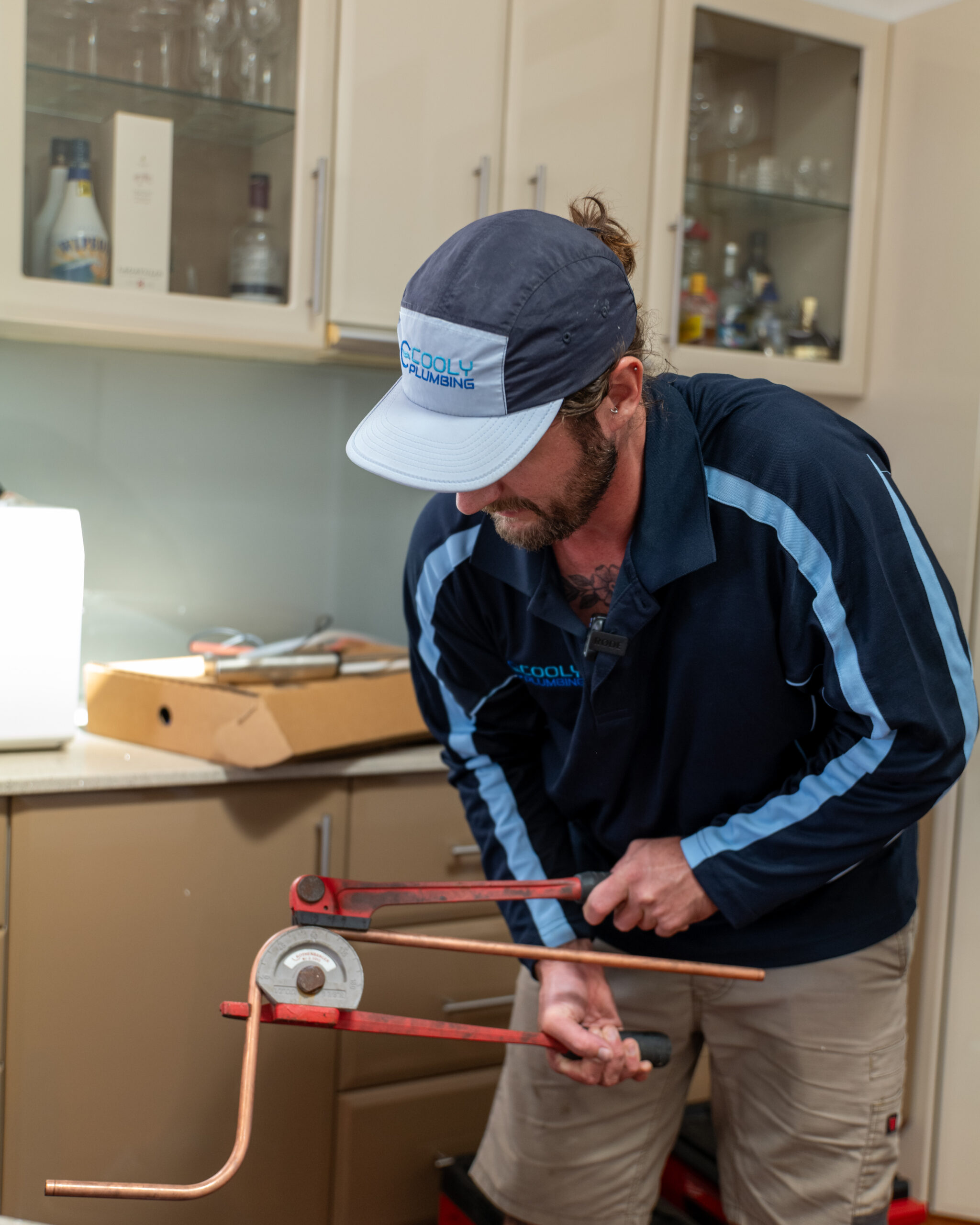 Plumber carefully bending copper pipe using a pipe bender tool, preparing custom plumbing connections during an installation