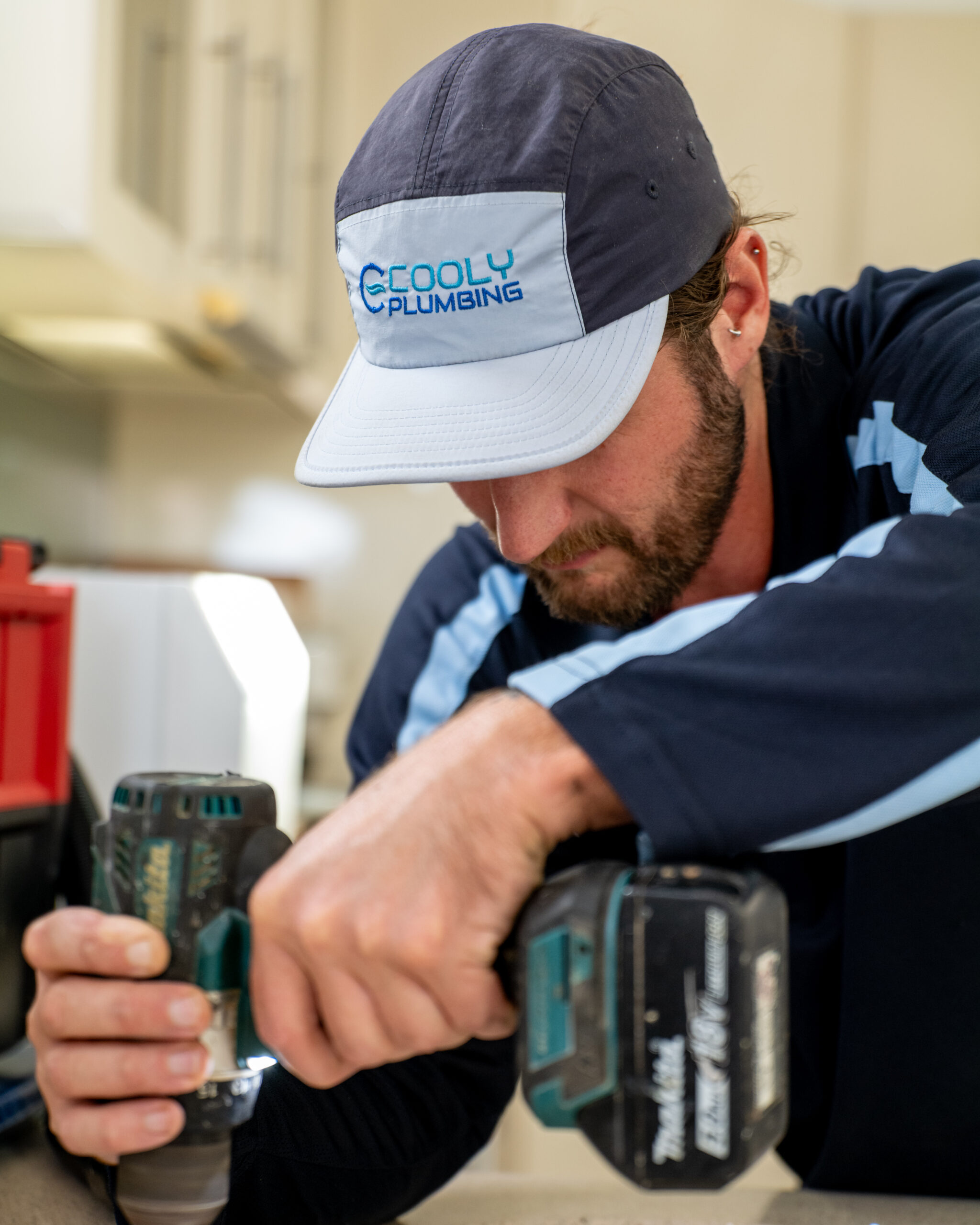 Cooly Plumbing technician carrying out pipe repairs on-site, fixing a damaged water line at a residential property